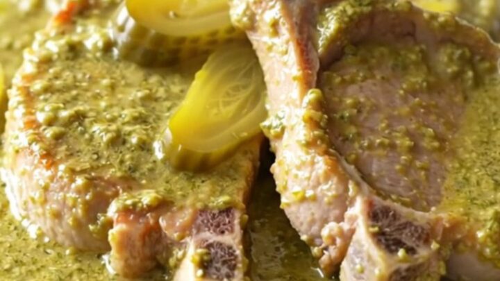 A high-angle shot of tender, braised boneless pork chops coated in a thick, creamy dill and pickle sauce in a slow cooker.