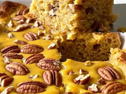 A top-down view of a rectangular baking dish filled with pumpkin bread pudding topped with chopped pecans.