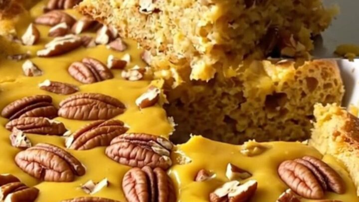 A top-down view of a rectangular baking dish filled with pumpkin bread pudding topped with chopped pecans.