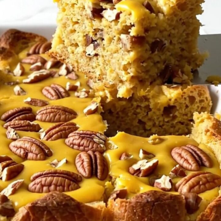 A top-down view of a rectangular baking dish filled with pumpkin bread pudding topped with chopped pecans.
