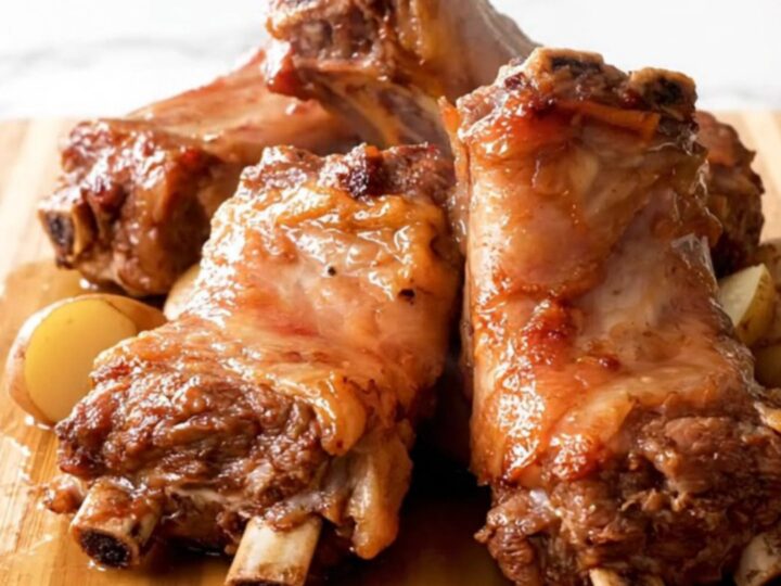 A top-down view of slow-cooked pork spareribs and baby potatoes in a black slow cooker insert.