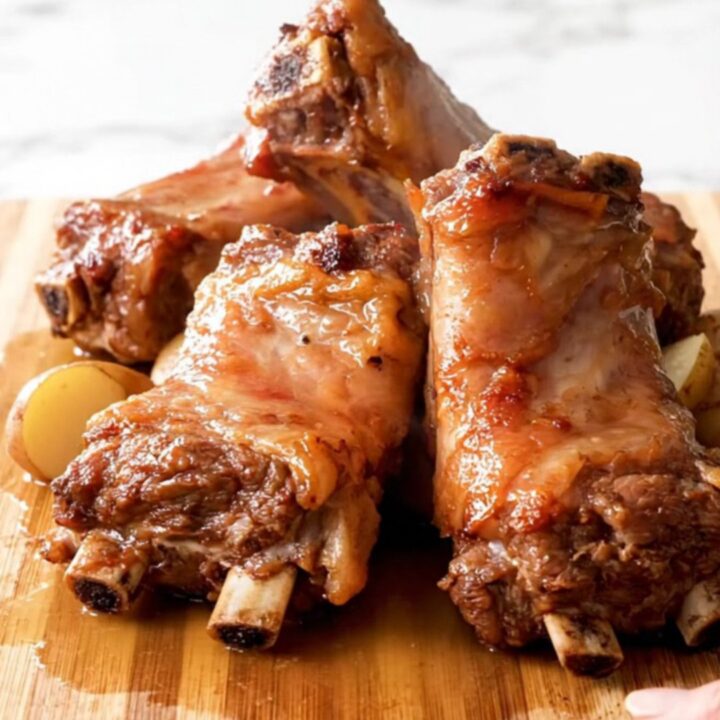A top-down view of slow-cooked pork spareribs and baby potatoes in a black slow cooker insert.