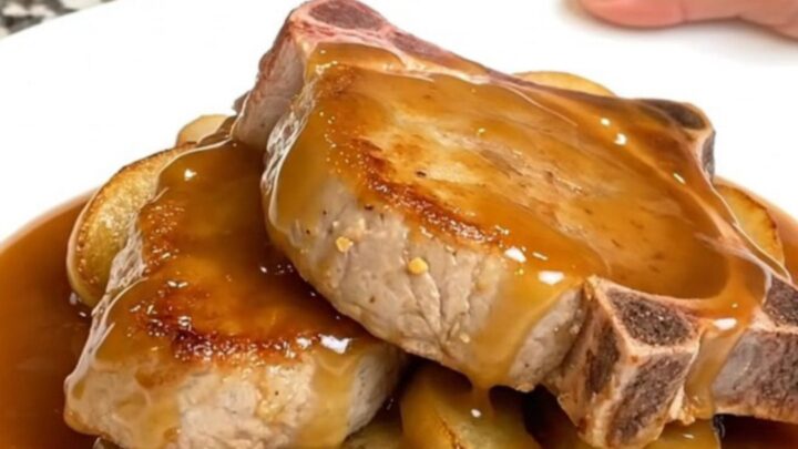 Close-up of tender caramel apple pork chops on a white plate with thick, glossy caramel sauce.