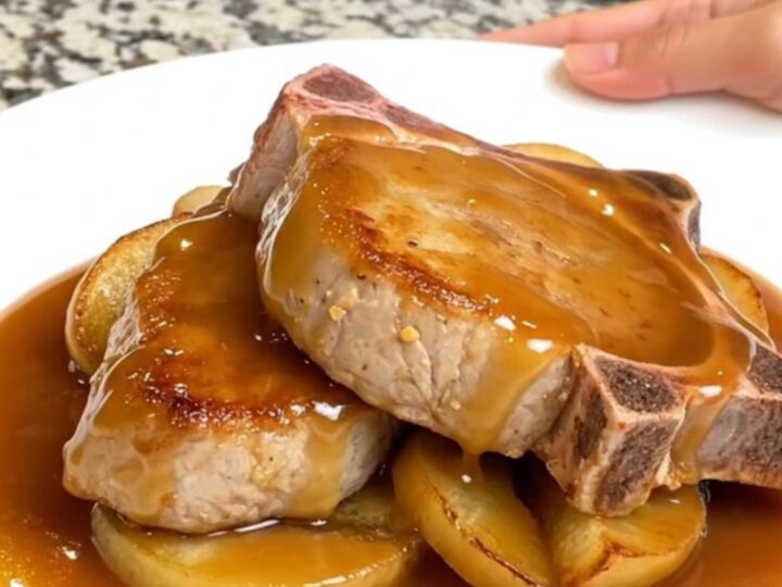Close-up of tender caramel apple pork chops on a white plate with thick, glossy caramel sauce.