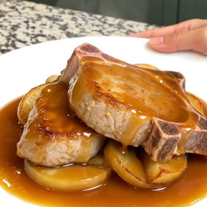 Close-up of tender caramel apple pork chops on a white plate with thick, glossy caramel sauce.