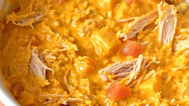 A warm, creamy queso dip with ground turkey and tomatoes in a black slow cooker.