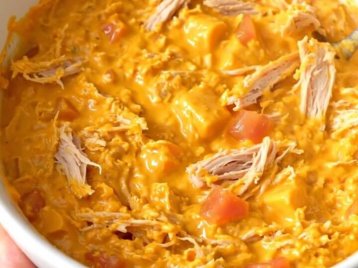 A warm, creamy queso dip with ground turkey and tomatoes in a black slow cooker.