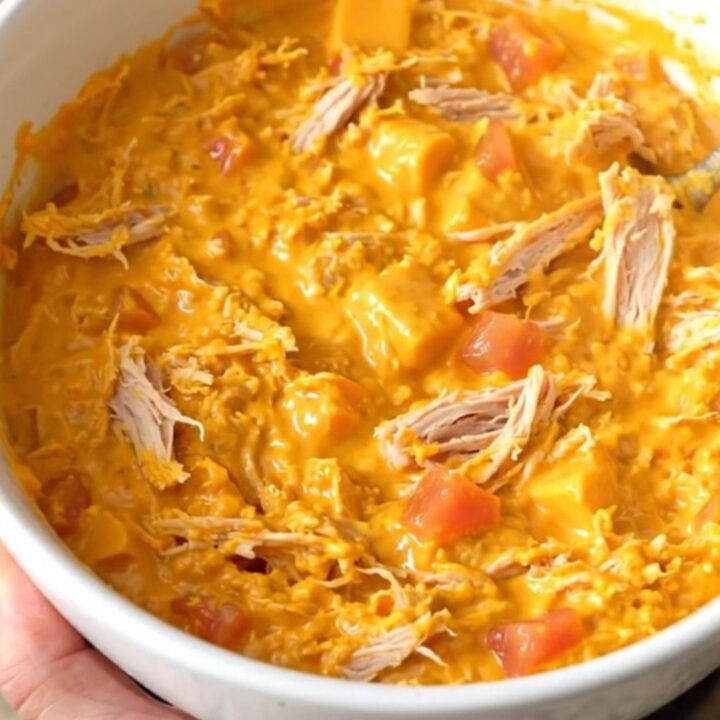 A warm, creamy queso dip with ground turkey and tomatoes in a black slow cooker.