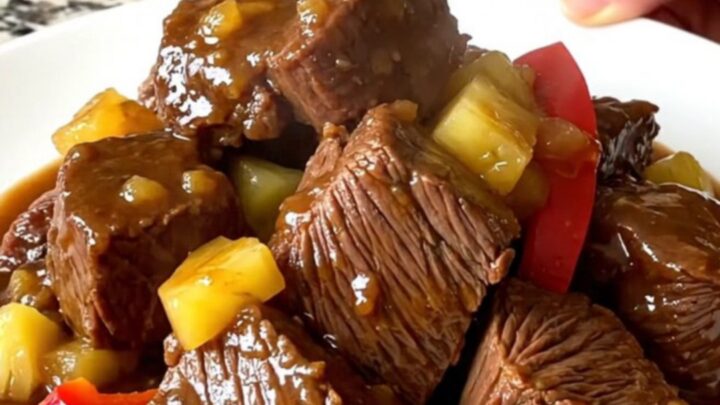 A close-up of tender Hawaiian chuck roast chunks with pineapple and peppers in a savory sauce.