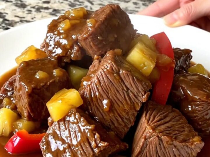 A close-up of tender Hawaiian chuck roast chunks with pineapple and peppers in a savory sauce.