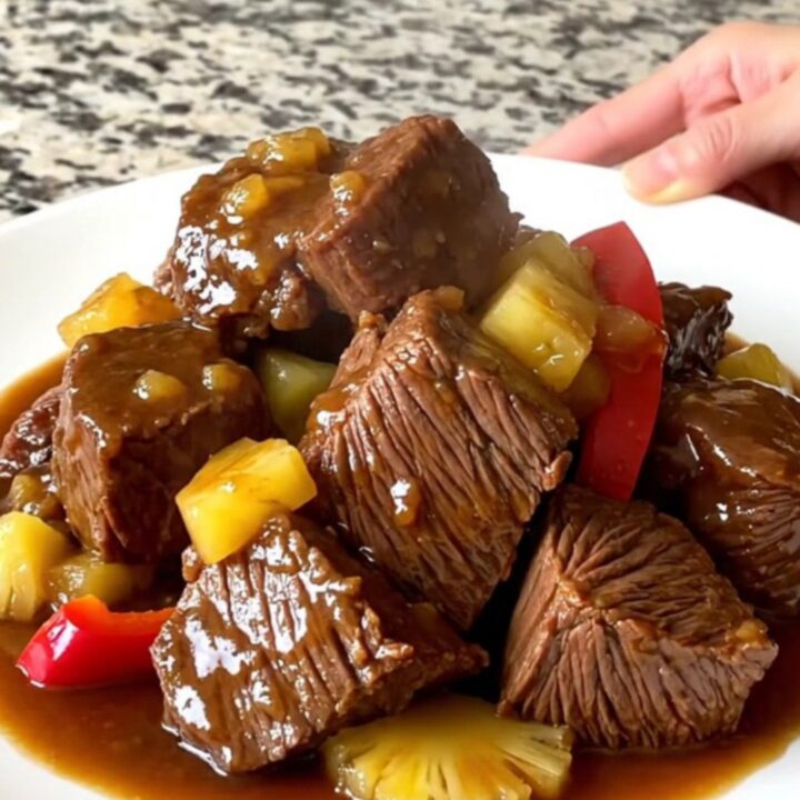 A close-up of tender Hawaiian chuck roast chunks with pineapple and peppers in a savory sauce.