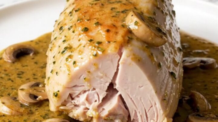 A slow cooker filled with turkey tenderloins, mushrooms, and a creamy Marsala sauce on a white quartz countertop.