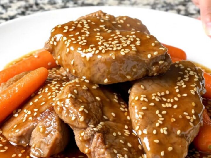 A top-down view of raw pork tenderloins and carrots in a slow cooker, ready to be seasoned.