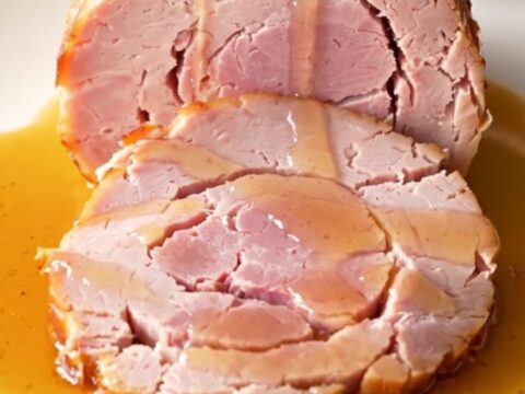 Close up of a spiral-sliced ham in a slow cooker with honey butter glaze.