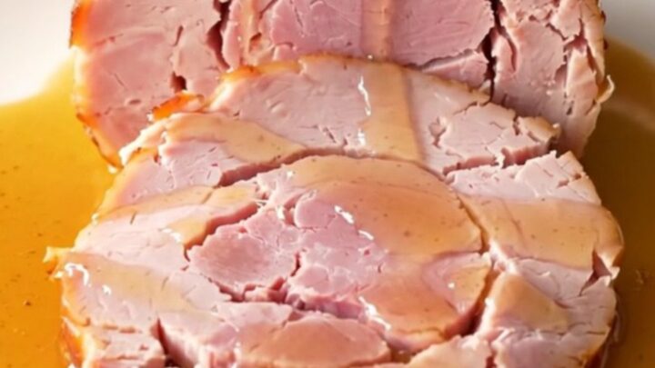Close up of a spiral-sliced ham in a slow cooker with honey butter glaze.