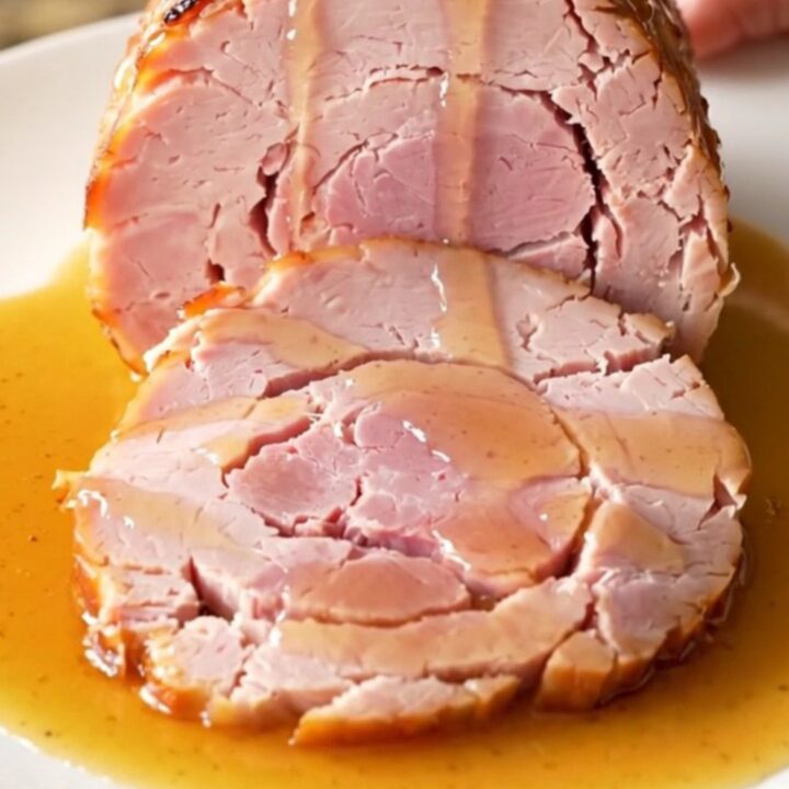 Close up of a spiral-sliced ham in a slow cooker with honey butter glaze.