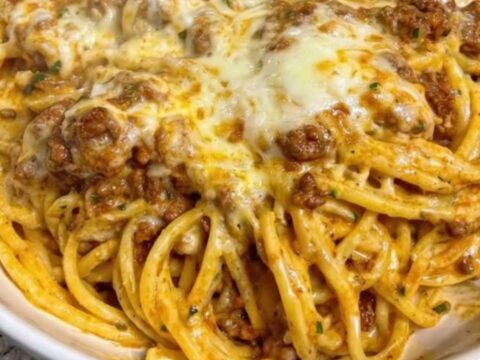 A wide white bowl filled with creamy garlic butter beef linguine, showing melted mozzarella and rich sauce.