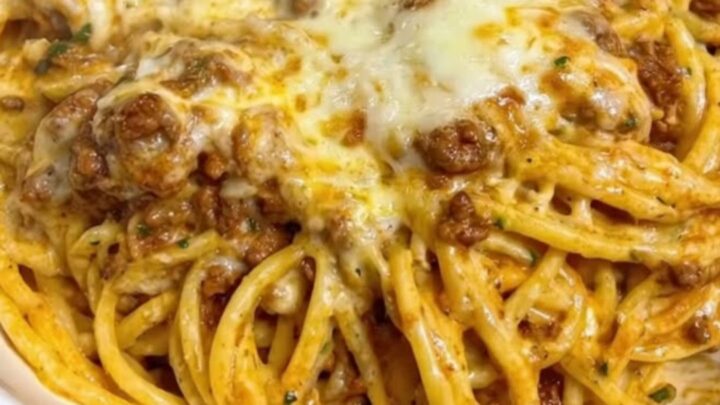 A wide white bowl filled with creamy garlic butter beef linguine, showing melted mozzarella and rich sauce.