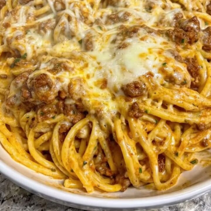 A wide white bowl filled with creamy garlic butter beef linguine, showing melted mozzarella and rich sauce.