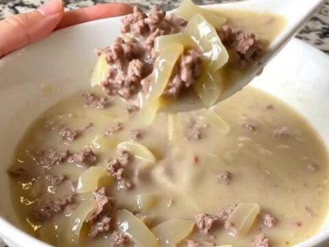 A warm bowl of creamy patty melt soup with visible ground beef, onions, and melted Swiss cheese.