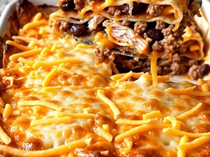 A golden, baked Mexican turkey tortilla lasagna with bubbly cheese edges in a white rectangular dish.