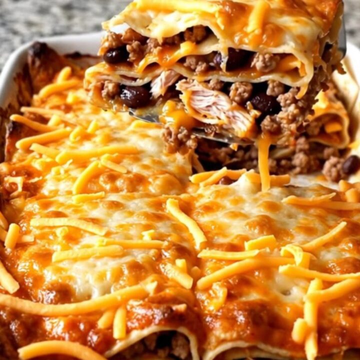 A golden, baked Mexican turkey tortilla lasagna with bubbly cheese edges in a white rectangular dish.