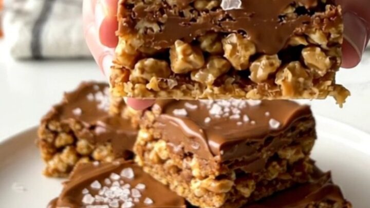 A close-up of a thick, layered Scotcheroo bar with a peanut butter base and a smooth chocolate-butterscotch top.