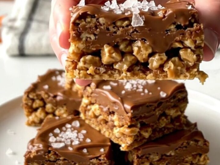 A close-up of a thick, layered Scotcheroo bar with a peanut butter base and a smooth chocolate-butterscotch top.