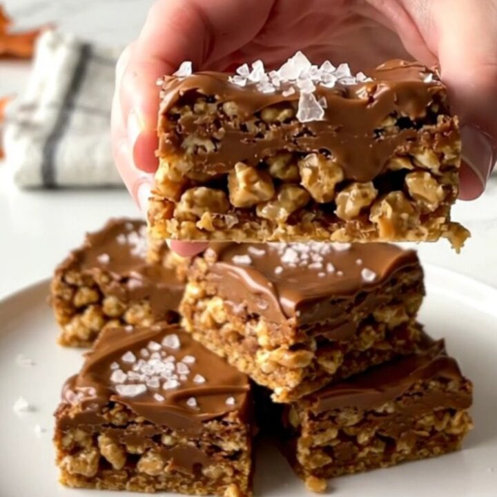 A close-up of a thick, layered Scotcheroo bar with a peanut butter base and a smooth chocolate-butterscotch top.