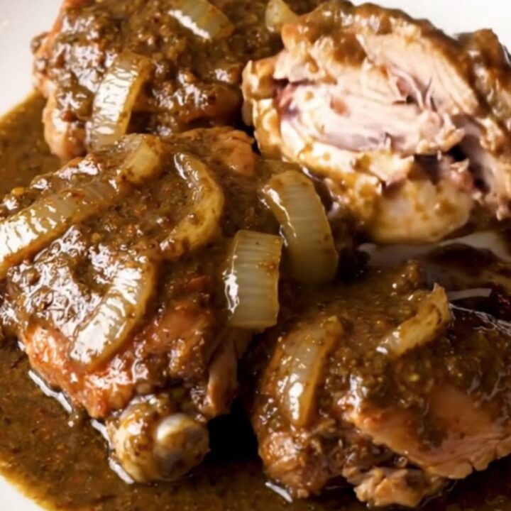 A close-up view of succulent, shredded turkey thighs coated in a rich, dark mole sauce in a slow cooker.