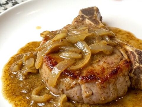 A plate of creamy smoked chile pork chops served with a rich sauce.