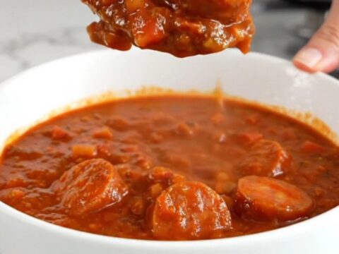 A close-up of a bowl of slow cooker smoked sausage chili showing sausage coins and beans.