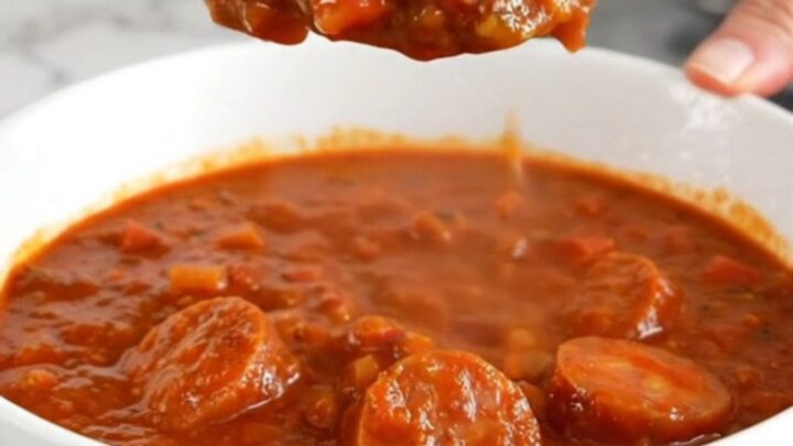 A close-up of a bowl of slow cooker smoked sausage chili showing sausage coins and beans.