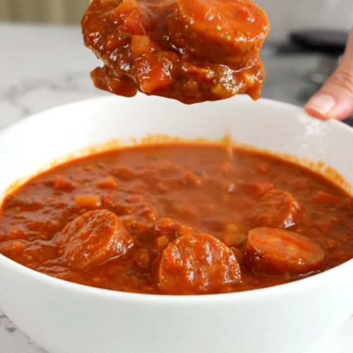 A close-up of a bowl of slow cooker smoked sausage chili showing sausage coins and beans.