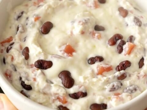 A creamy black bean queso dip in a slow cooker topped with diced tomatoes and beans.