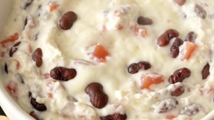 A creamy black bean queso dip in a slow cooker topped with diced tomatoes and beans.