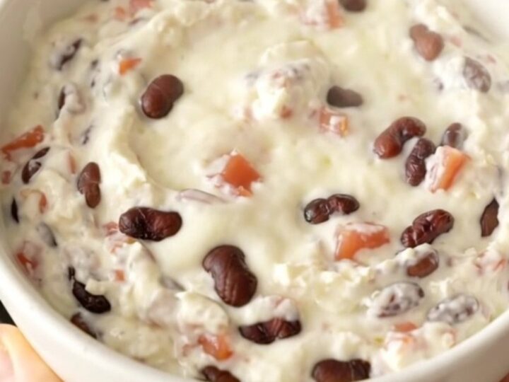 A creamy black bean queso dip in a slow cooker topped with diced tomatoes and beans.