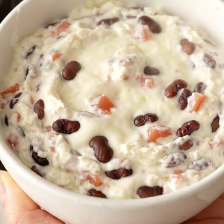 A creamy black bean queso dip in a slow cooker topped with diced tomatoes and beans.