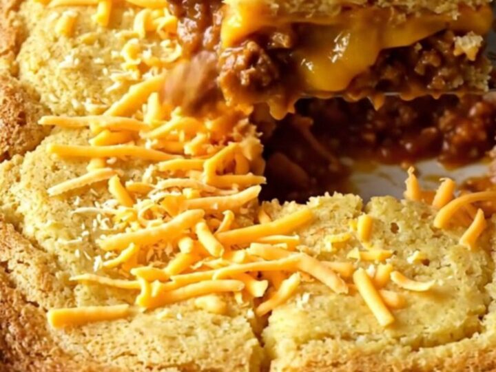 A golden, freshly baked turkey chili cornbread bake in a ceramic dish, with melted cheddar on top.