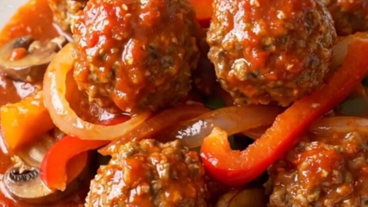A bowl of chicken meatball cacciatore with peppers and mushrooms in a rich tomato sauce.