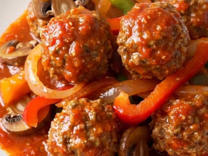 A bowl of chicken meatball cacciatore with peppers and mushrooms in a rich tomato sauce.