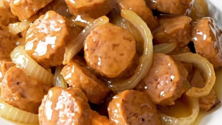 A close-up of a slow cooker filled with golden-brown chicken sausage coins, tender sweet potato cubes