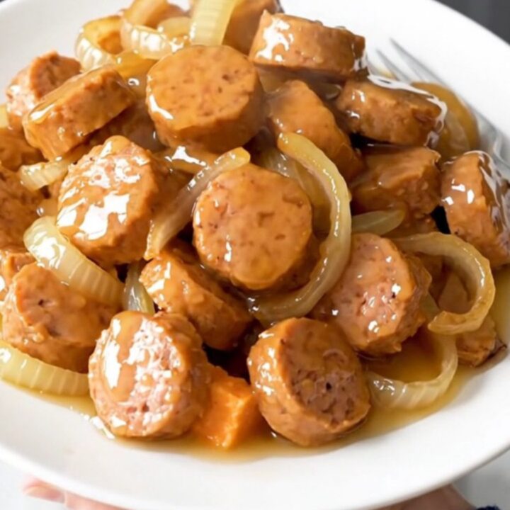 A close-up of a slow cooker filled with golden-brown chicken sausage coins, tender sweet potato cubes