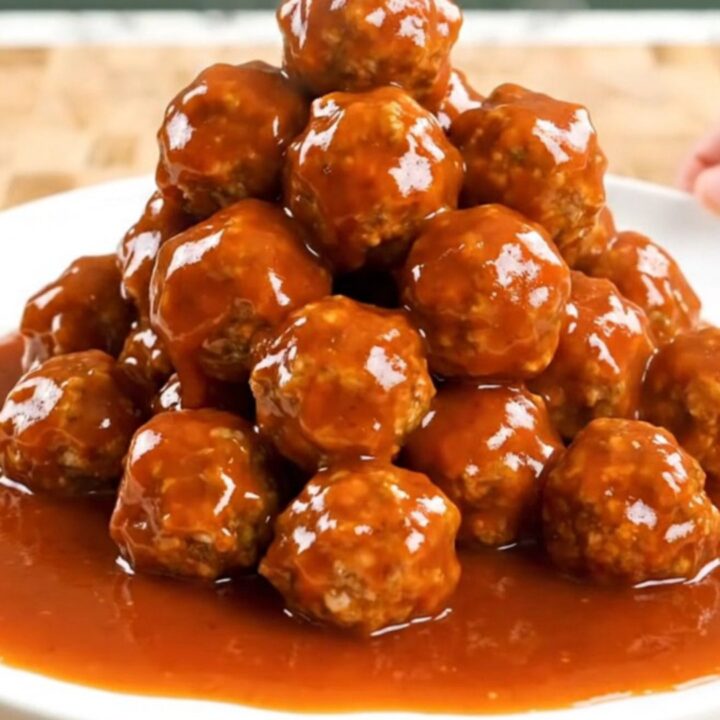 A close-up of firecracker turkey meatballs in a slow cooker, coated in a thick, vibrant orange-red sauce.