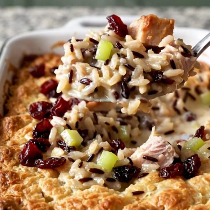 A creamy turkey and wild rice bake in an enameled dish with cranberries on top.