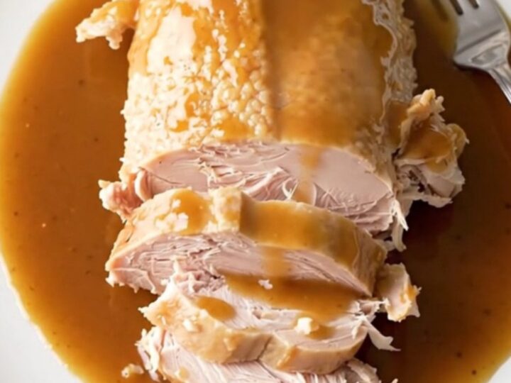 A slow cooker filled with a cooked turkey breast, sweet potato chunks, and a rich maple bourbon sauce.