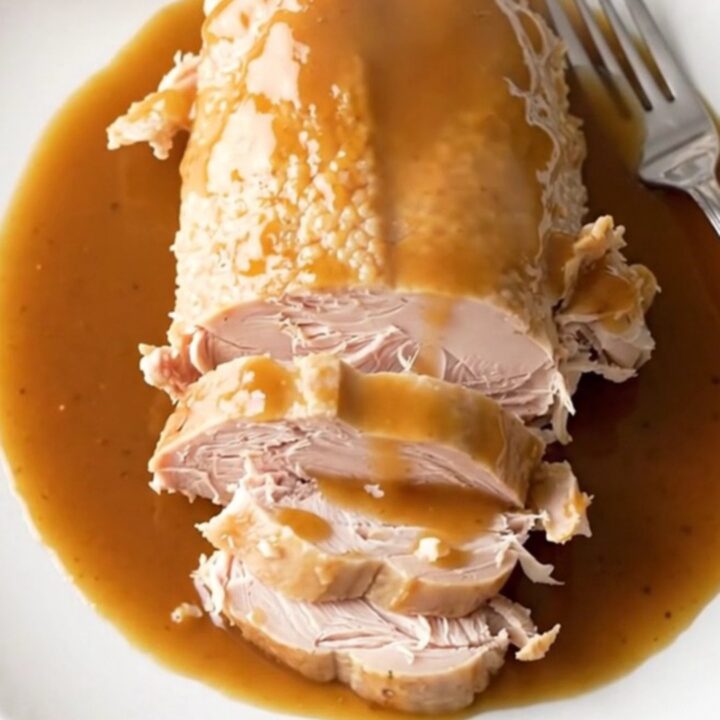 A slow cooker filled with a cooked turkey breast, sweet potato chunks, and a rich maple bourbon sauce.