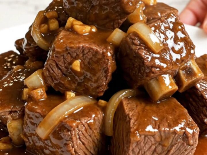 Slow cooker filled with tender beef cubes, onions, and a rich, glossy brown sugar garlic sauce.