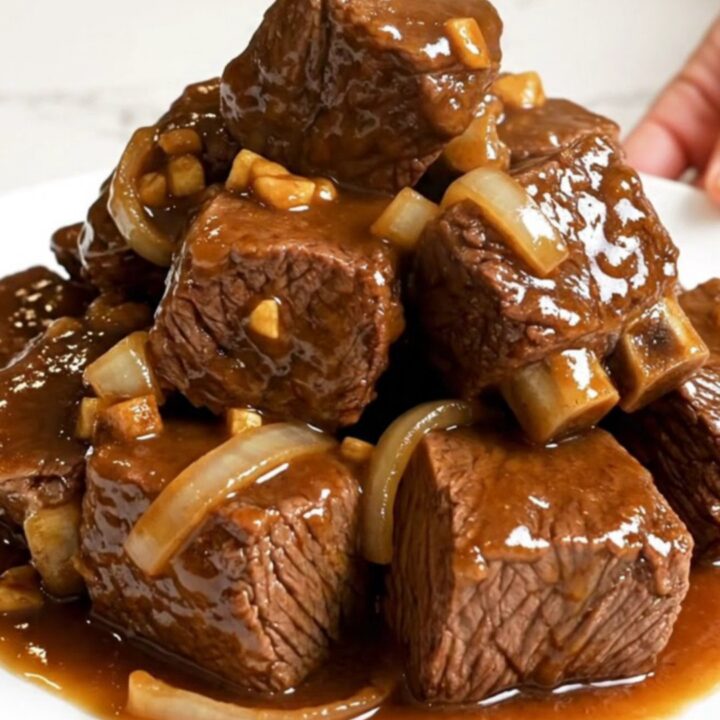 Slow cooker filled with tender beef cubes, onions, and a rich, glossy brown sugar garlic sauce.