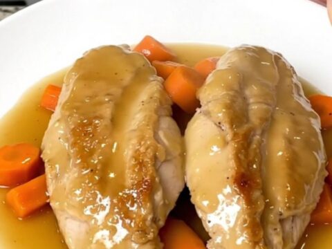 A white plate featuring tender honey ginger chicken breasts topped with glazed carrot coins.